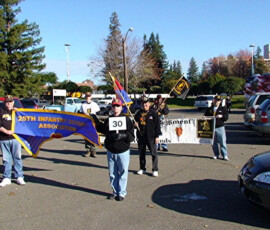 Wolfhound veterans march behind the 25th Infantry Division Association and 27th Regiment banners.